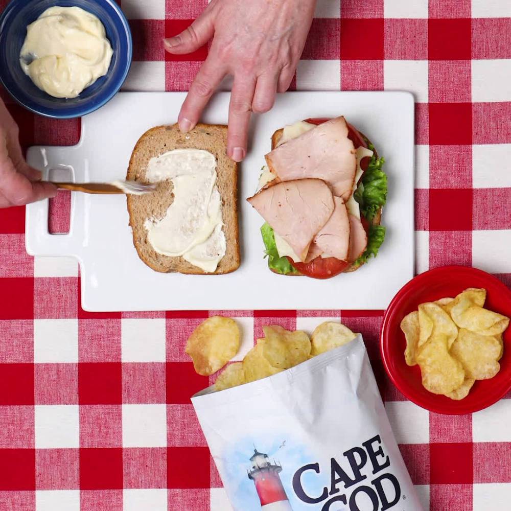 Cape Cod Kettle Chips Sea Salt served with a sandwich on a red checkered tablecloth, ideal for lunch or snack pairing.